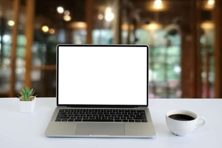 Front view of open laptop computer notebook with blank monitor white screen display on work table desk. Workspace office modern for job business online communication technology in shop or home indoor.の写真素材