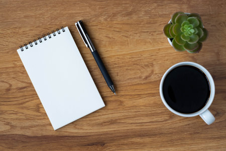 Top view of open school notebook with blank pages, coffee cup and pen for taking write notes on table background. Flat lay, creative workspace office. Business-education concept with copy space.の写真素材