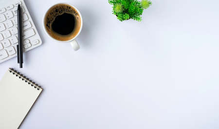 Top view above of White office desk table with keyboard, notebook and notepad, coffee cup with equipment office supplies. Business and finance concept. Workplace, Flat lay with blank copy space.の写真素材