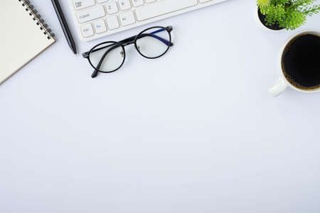 Top view above of White office desk table with keyboard, notebook and coffee cup, glasses. Business and finance concept. Workplace, Flat lay with blank copy space.の写真素材