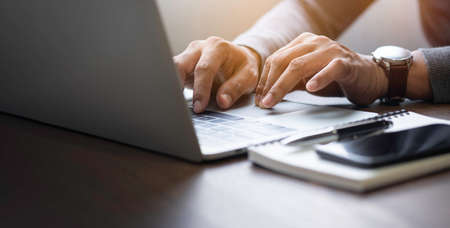 Close-up of man hands using and typing keyboard of laptop computer on office desk. Workspace,...