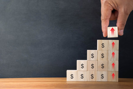 Hand arranging wood blocks stacking as step stair on wooden table background. Business investment and finance accounting concept for growth success process with copy space.の写真素材