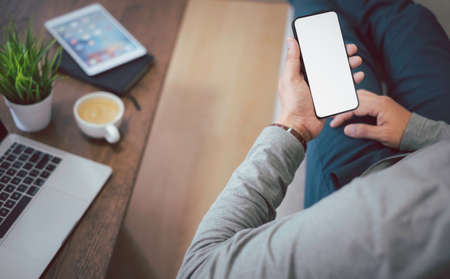 Shot of man hand using, holding smartphone or mobile mockup with blank white screen display. Phone technology, digital modern design can use touch screen with copy space.の写真素材