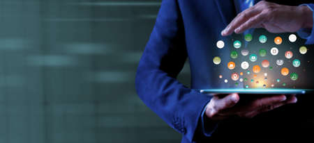 Businessman holding tablet showing virtual icons app. Social digital, Analysis strategy sale marketing and economic data online network connection. Business finance and digital technology concept.の写真素材