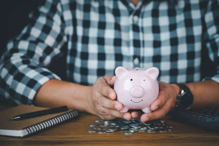 Piggy bank on hand for account save money. Planning step up, saving money for future plan, retirement fund. Business investment-finance accounting concept.の写真素材