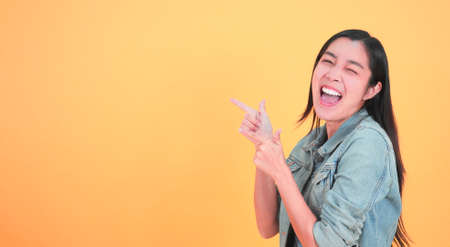 Shocked, amazed young beautiful asian woman 20s standing looking at camera with excited smile isolated on yellow background studio portrait. Facial, surprised and happy adorable rejoices success.の写真素材
