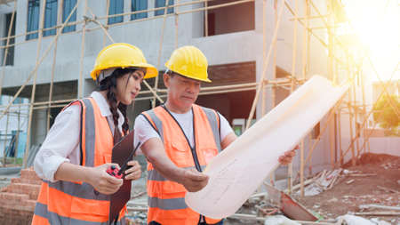 Asian woman civil engineer or Architect, inspector with contractor, foreman or worker wear safety...