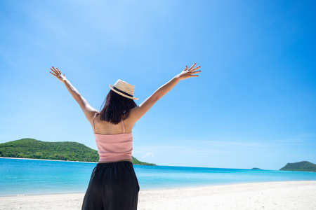 Back of woman tan skin wearing pink tank top and straw hat with standing arms outstretched on sky. looking into the sea and fresh sky. Summer travel. Relax, Holiday and tropical, comfortable concept.の写真素材