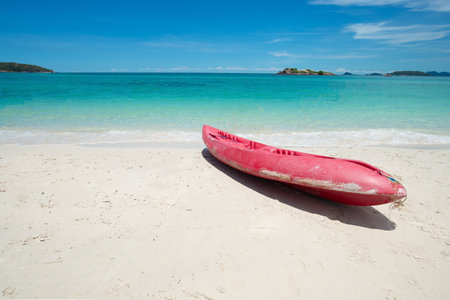 Red Kayak at the tropical beach at beautiful Clear day. Beautiful clear sand beach and tropical light blue sea. Soft wave blue ocean on sandy beach. Sallow water, Clear water. Seaside. Copy space.の写真素材