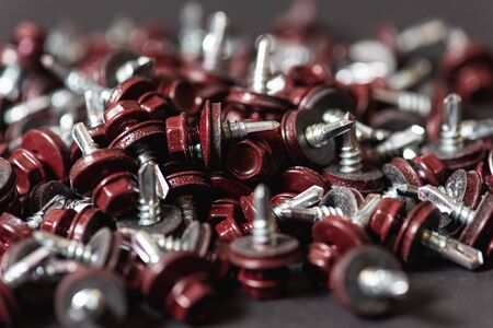 Top view of roofing screws background texture. Red roofing screws background. A bunch of...
