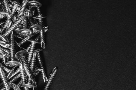 Galvanized screws with a semicircular head and a cross-shaped slot and a washer on a dark background. Close upの写真素材