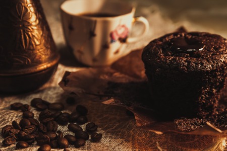 Chocolate cake on parchment with a cup of coffee, copper pots and coffee beans breakfastの写真素材