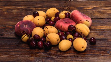 Fruits fig peaches, apricot and cherry on dark wooden table