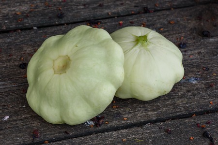 Two ripe pattypan squash lie on the old wooden table in the gardenの写真素材
