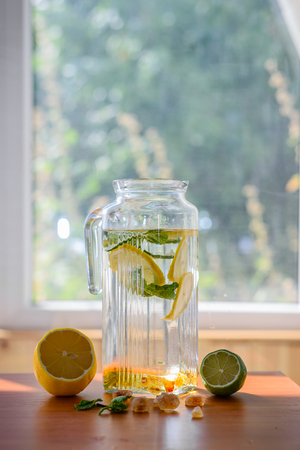 Homemade lemonade in pitcher with ingredients on window background. sweet and sour refreshing tasteの写真素材