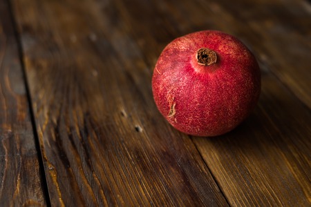 Red and ripe pomegranate lying on the dark wooden table. space for text.の写真素材
