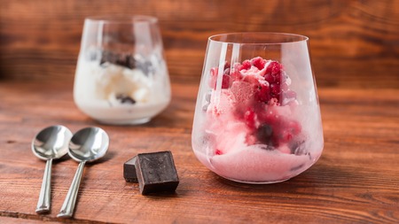 Sweet desert. White and pink ice cream in glass on wooden table.の写真素材