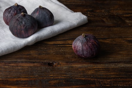 Ripe seasonal figs on the cloth and one on a wooden surface.の写真素材