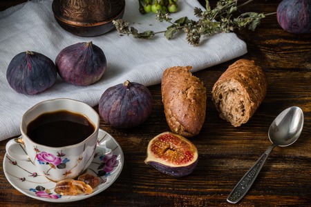 Cup of coffee with fresh bread and some ripe figs on wooden surfaceの写真素材