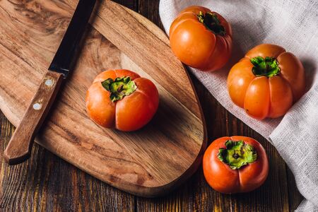 Persimmons with Knife on Wooden Cutting Boardの写真素材