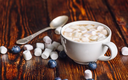 Cup of Coffee with Marshmallow with Scattered Few Blueberries and Some Marshmallows, and Spoon on Backdrop.の写真素材