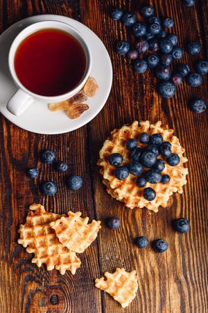 Cup of Tea with Blueberries and Whole and Broken Belgian Waffles on Wooden Background. Vertical Orientation.の写真素材