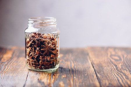 Jar of Star Anise Fruits and Seeds on Wooden Table. Copy Space on the Right.の写真素材