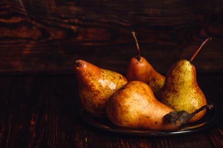 Few golden pears on metal plate over wooden background.の写真素材