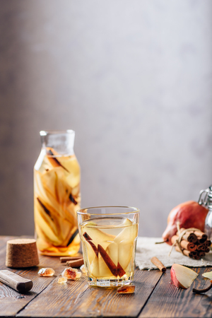 Flavored Water in Glass and Bottle with Sliced Pear, Cinnamon Stick, Ginger Root and Some Sugar. Ingredients on Wooden Table. Vertical Orientation.の写真素材