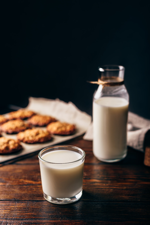 Glass of Milk with Bottle and Oatmeal Cookies on Parchment Paper. Copy Space on the Top.の写真素材