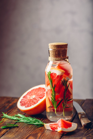 Bottle of Water Infused with Sliced Raw Grapefruit and Fresh Springs of Rosemary. Vertical Orientation. Copy Space on the Top.の写真素材