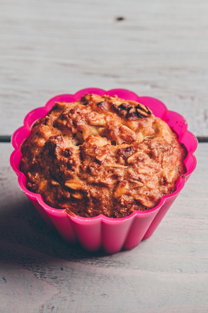 Cooked oatmeal muffin in a pink silicone bake ware over light woodenの写真素材