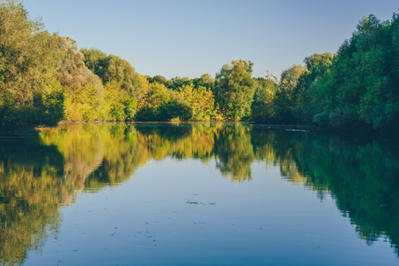 Blue lake in the autumn forest at sunset.の写真素材