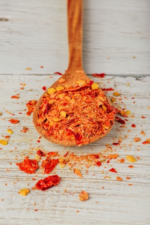 Spoonful of crushed red chili pepper over wooden backgroundの写真素材
