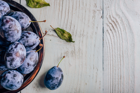 Ripe plums on metal plate over light wooden surface. Copy spaceの写真素材