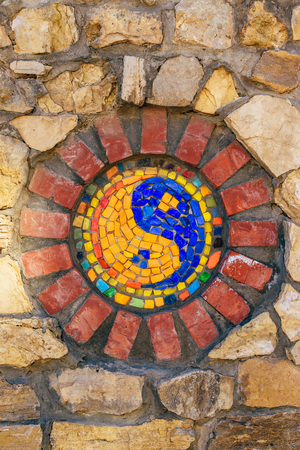 Circular mosaic religious symbol of Yin and yang on stone wall.の写真素材