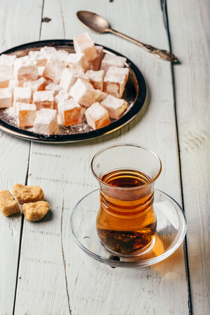 Tea in arabic glass with turkish delight Rahat Lokum over wooden surfaceの写真素材