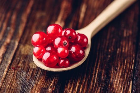 Spoonful of red currant over the dark wooden surfaceの写真素材