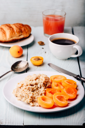 Breakfast set. Porridge with sliced apricot, cup of coffee, glass of grapefruit juice and croissantの写真素材