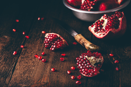 Pomegranate pieces with knife on rustic wooden surface.の写真素材