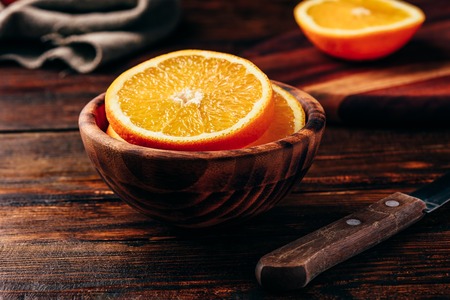 Sliced orange in a wooden bowl in rustic settingの写真素材