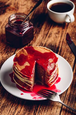 Stack of pancakes with berry fruit marmalade on plate over wooden surfaceの写真素材