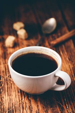 Black coffee in white cup with sugar and cinnamon sticksの写真素材