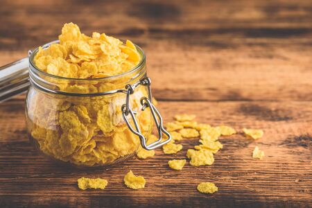 Corn flakes in a glass jar on wooden surfaceの写真素材