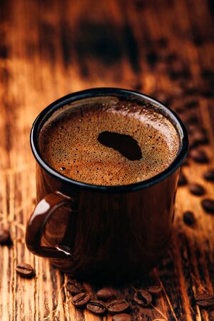 Brewed black coffee in metal mug over wooden surfaceの写真素材