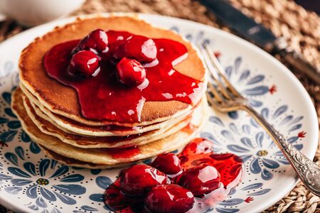 Stack of pancakes with dogwood berry marmalade on white plate with ornateの写真素材