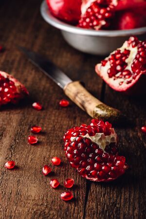 Pomegranate fruits with knife on rustic wooden surface.の写真素材