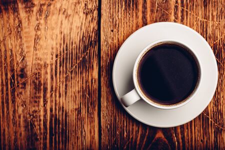Black coffee in white cup over wooden surfaceの写真素材