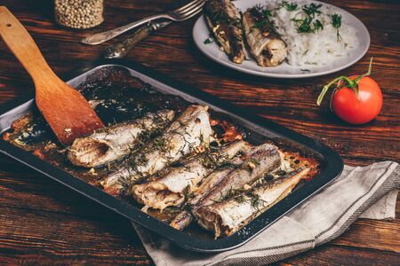 Baked fish carcasses on baking sheet over wooden surfaceの写真素材