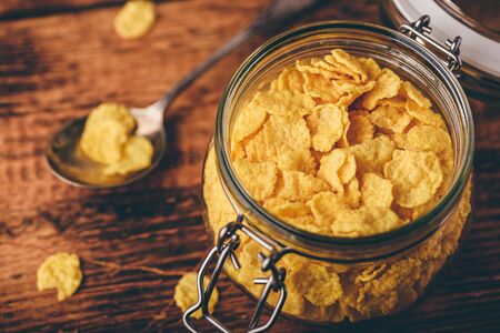 Jar of corn flakes for breakfast on wooden surfaceの写真素材